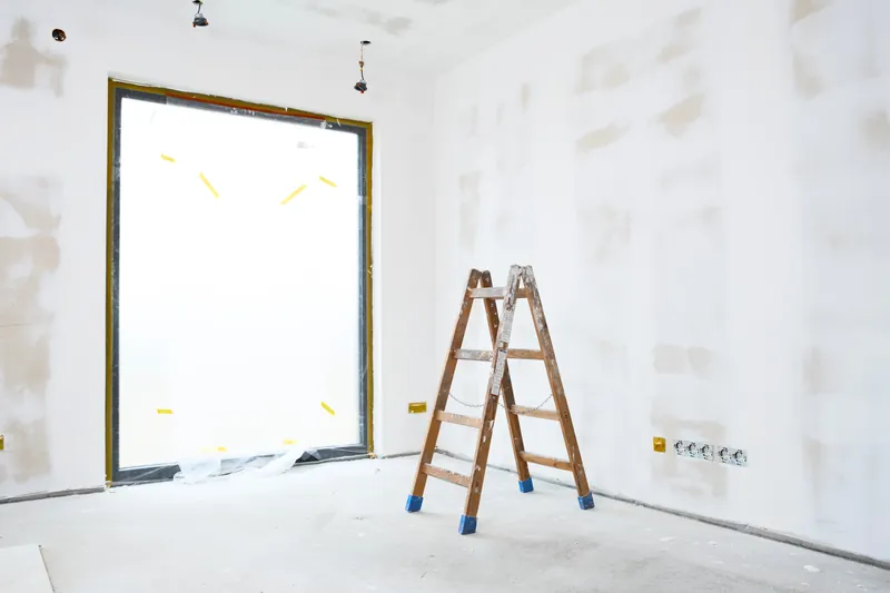 Frisch gespachtelter, heller Raum mit Malerleiter vor der Wand