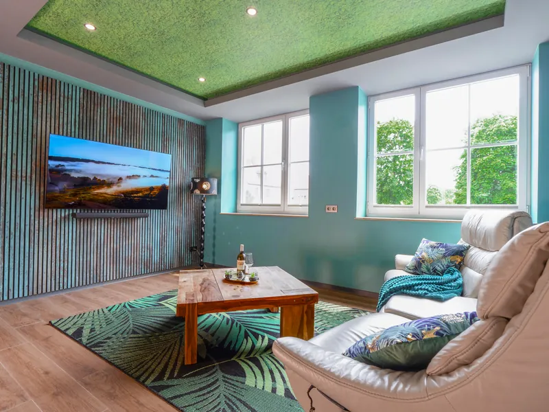 Wohnzimmer mit Sofa, Lamellenwand und grüner Moosdecke