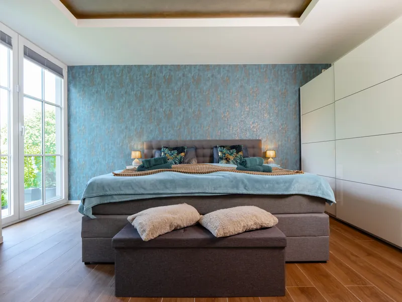 Schlafzimmer mit blau-kupferner Wandgestaltung hinter dem Bett
