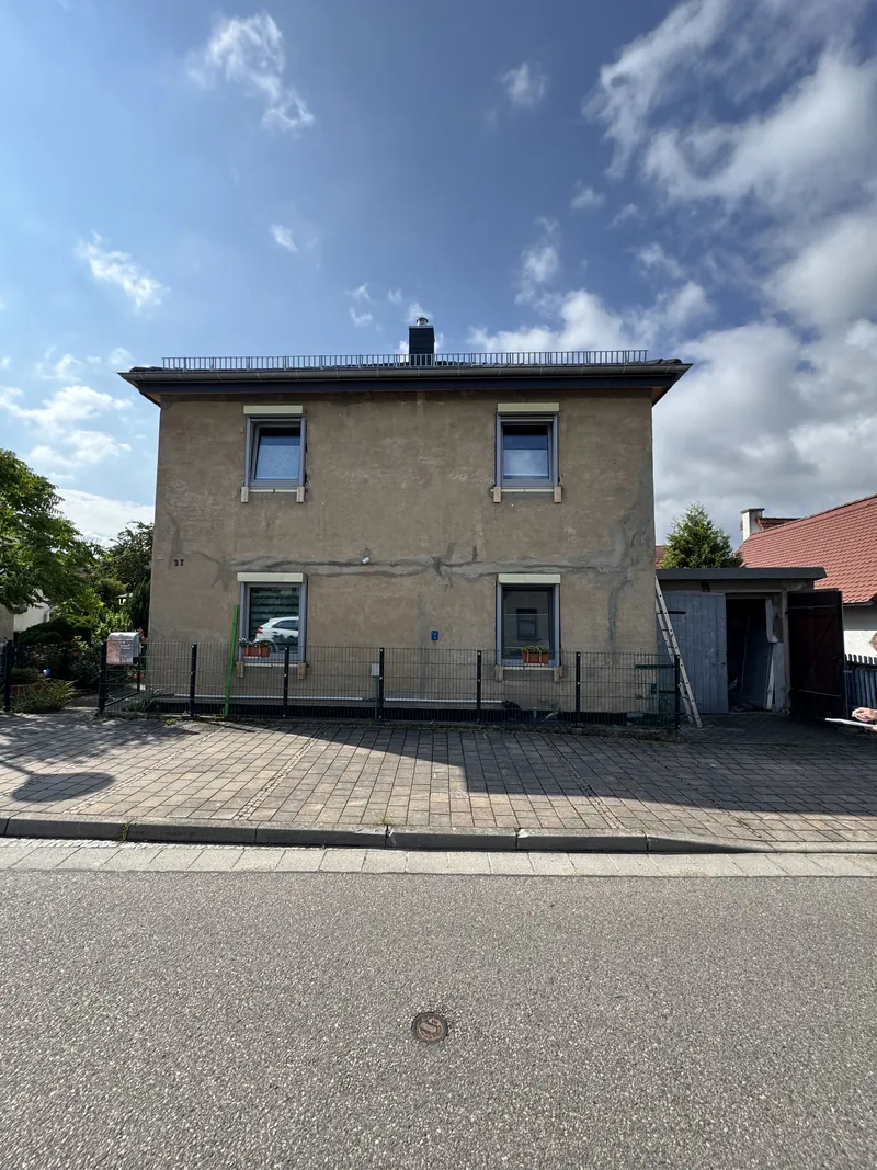 Wohnhaus mit grauem, verwittertem Putz vor dem Fassadenanstrich