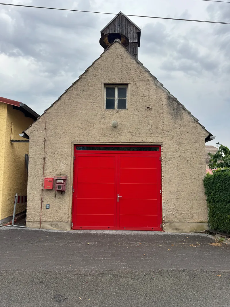 Altes Feuerwehrhaus mit rotem Tor vor dem Anstrich