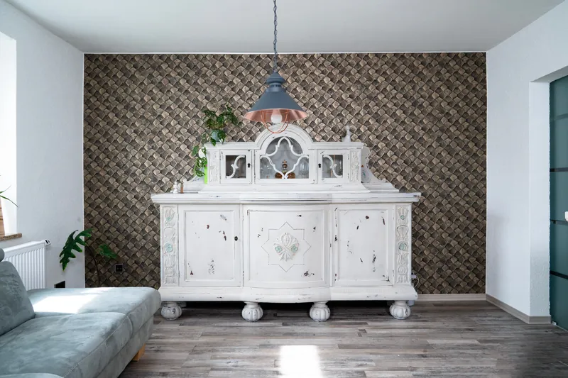 Weißes Vintage-Buffet vor einer Wand mit goldener Strukturtapete