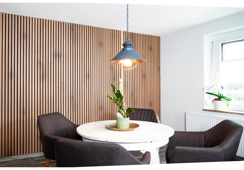 Essbereich vor einer Wand mit Akustikpaneelen aus Holzlamellen