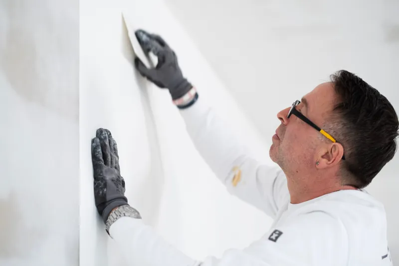 Maximilian Petzold spachtelt eine Wand glatt