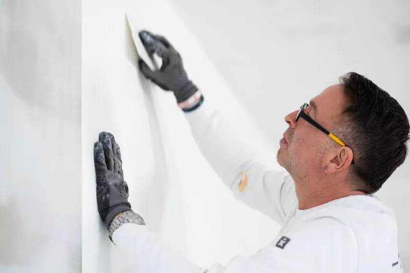 Maximilian Petzold spachtelt eine Wand glatt